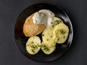 Котлеты из рыбы тресковых пород с куриным филе и свиным шпиком с отварным картофелем и сливочным соусом.